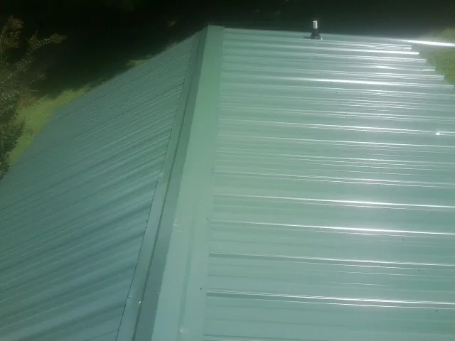 New green metal panels meeting at the ridge of a roof — Flat Roof Repair work by our crew in Long Beach