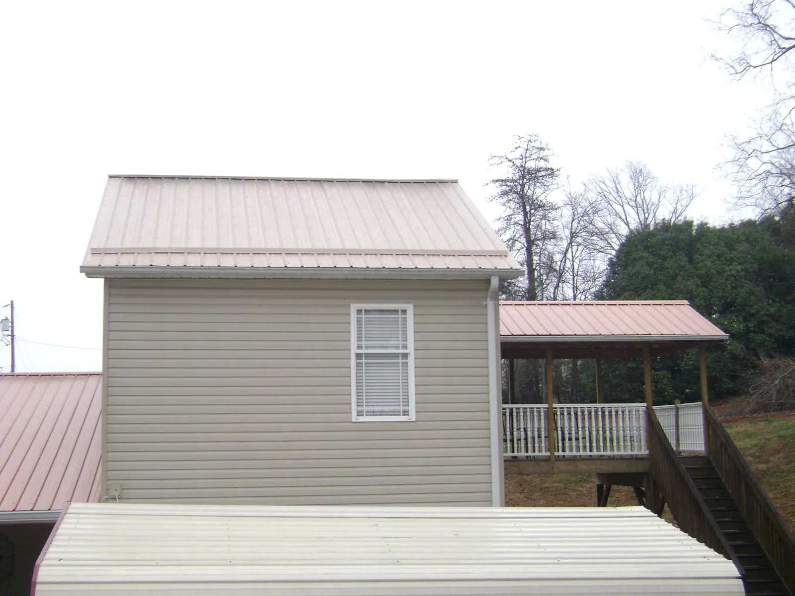 Tan metal roofs on a two story addition and attached porch, from a Roof Replacement job in Long Beach